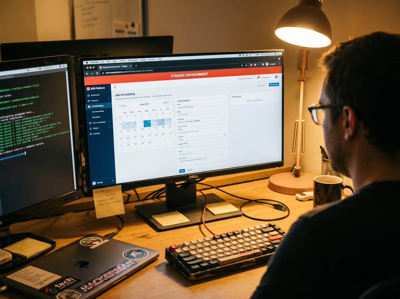Over-the-shoulder view of a staging environment on a monitor with passing automated tests on a second screen.